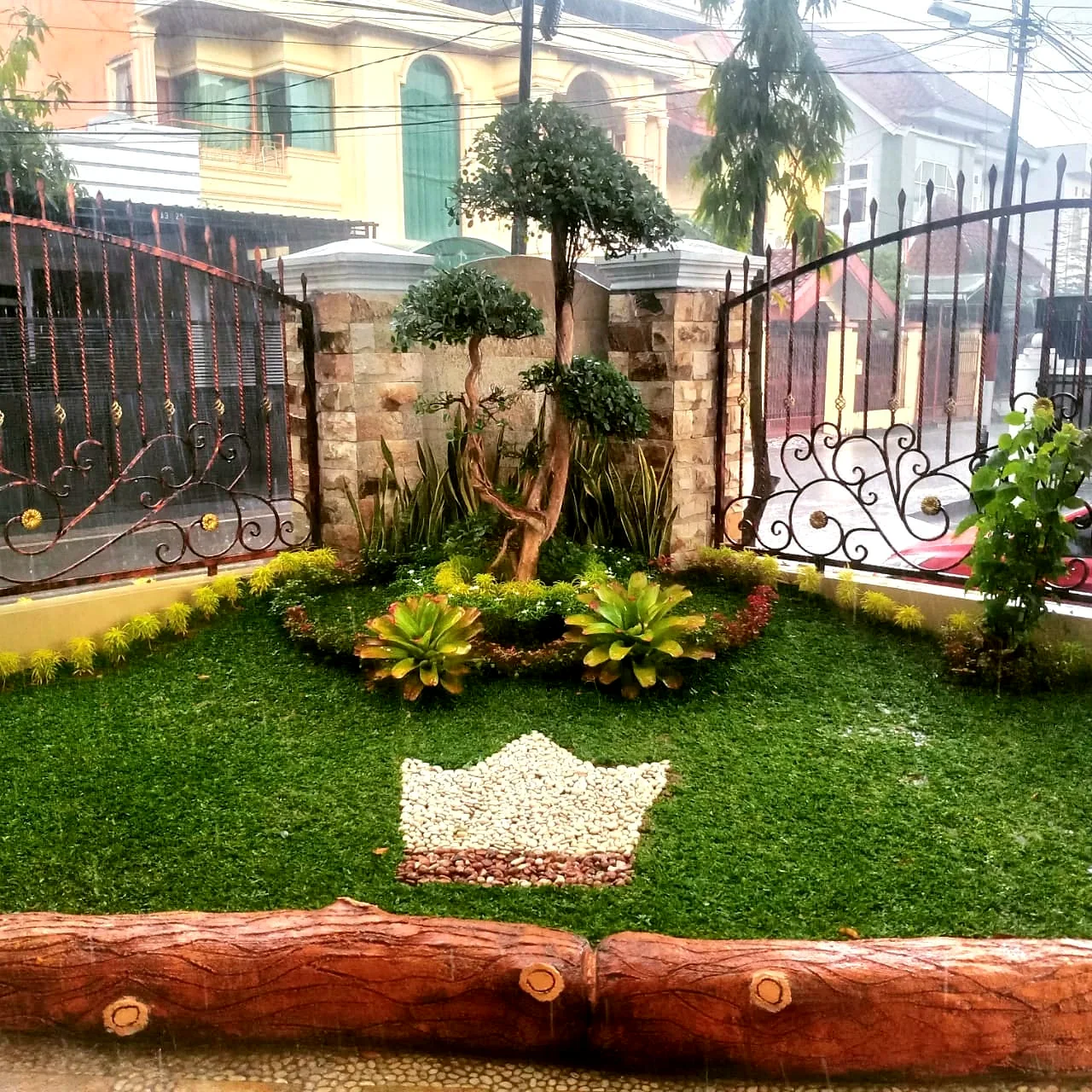 Taman minimalis depan rumah dengan komposisi rumput dan batu putih